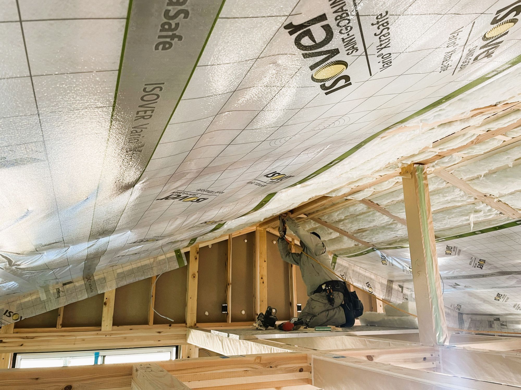 小屋裏で断熱材と気密シートを施工している現場の様子