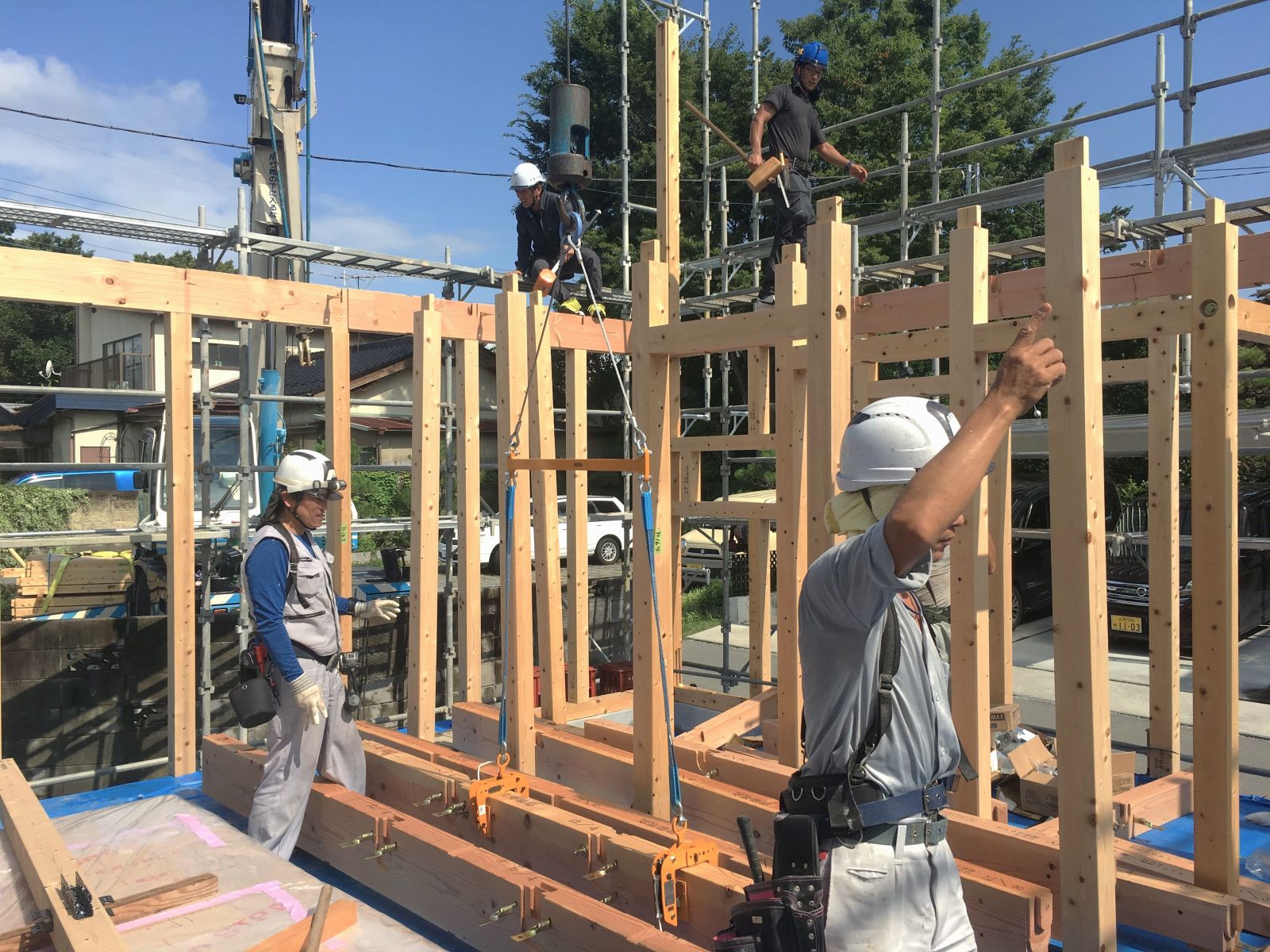 木造住宅の上棟現場で、職人が連携しながら構造材を組み上げている自社施工の様子