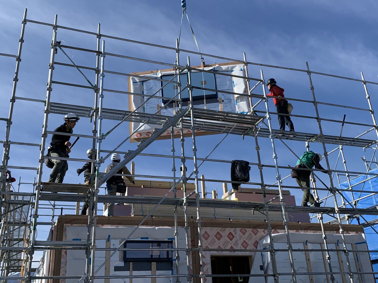 大型パネル工法による建て方工事。自社の職人が連携し、パネルの建て込みと位置確認を行っている