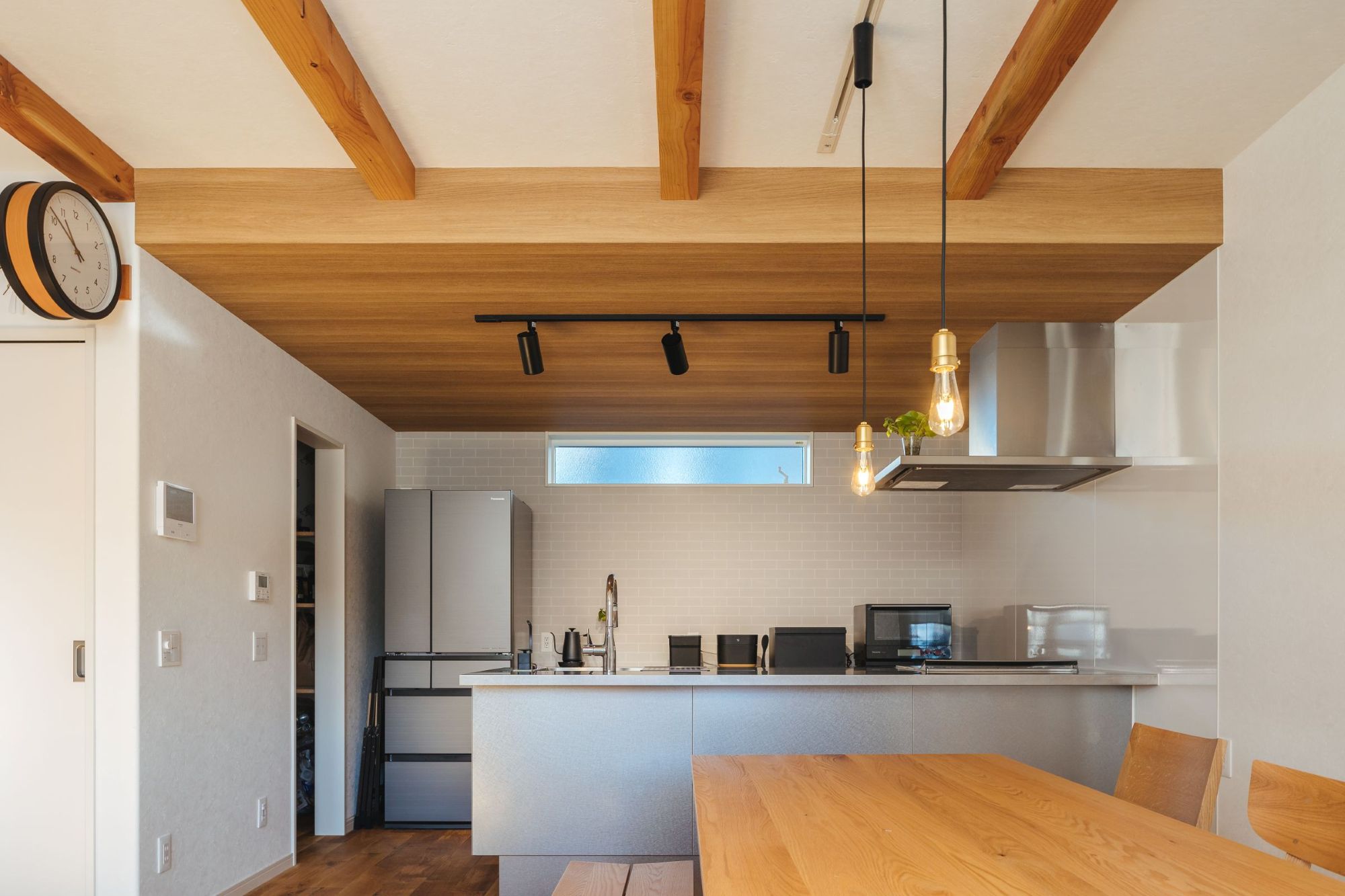 梁と木の天井が印象的な、山梨の木の家のキッチンとダイニング空間