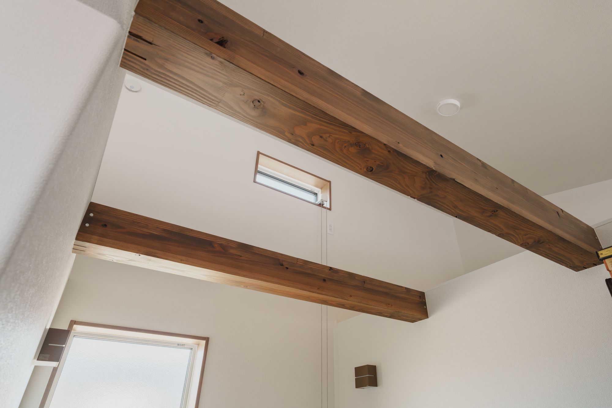 吹き抜け空間に現し梁と高窓を設けた室内の内観