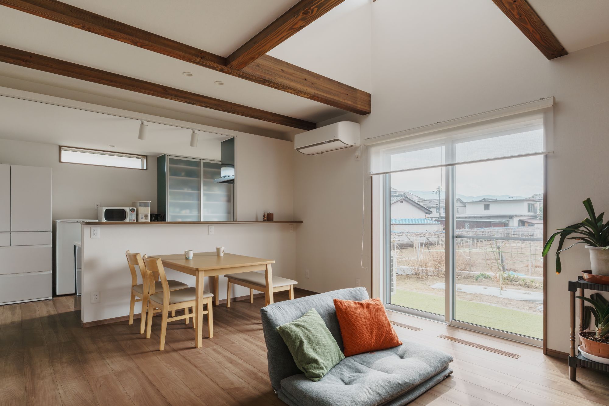 現し梁のあるLDKで、リビングと庭が掃き出し窓でつながる内観