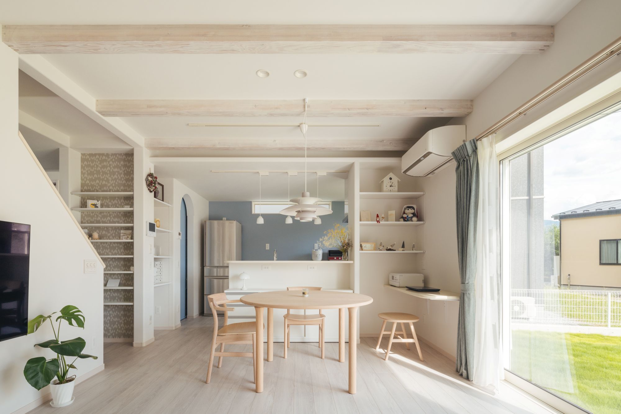 梁あらわし天井のあるLDKで、ダイニングとキッチンが一体となった明るい空間