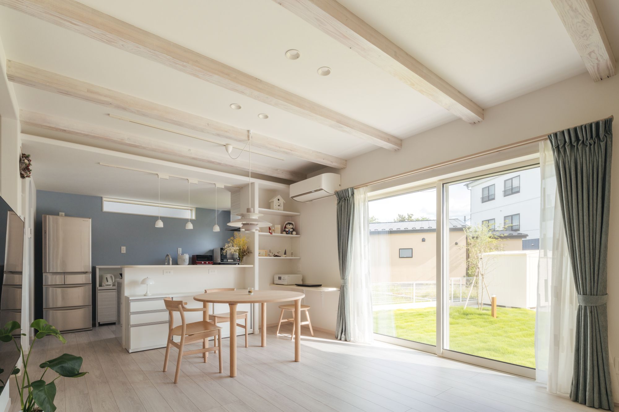 南面の大きな掃き出し窓から光が入る、梁あらわし天井の明るいLDK空間