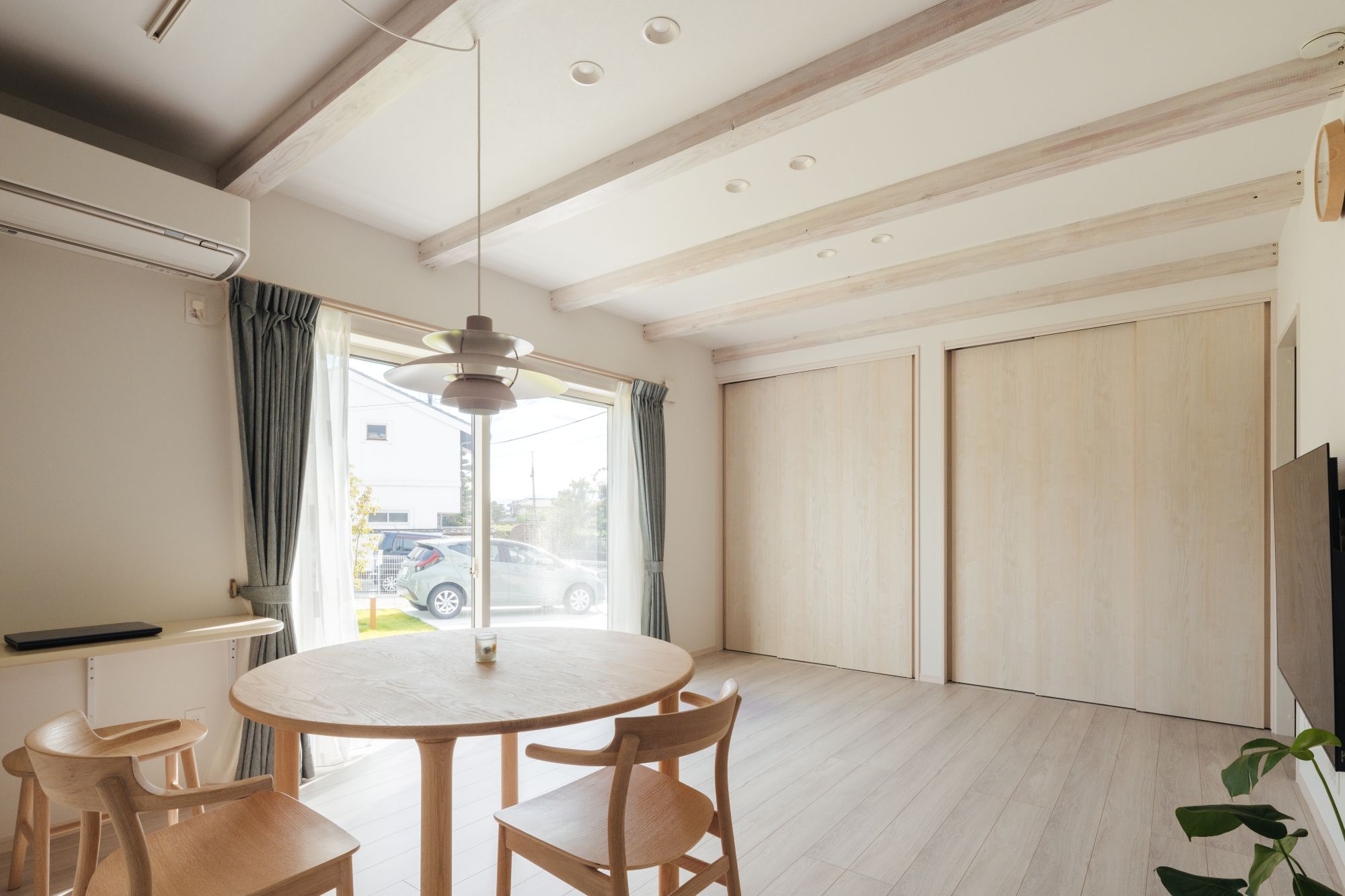 梁あらわし天井のあるダイニングと、壁面に設けた引き戸収納のある空間