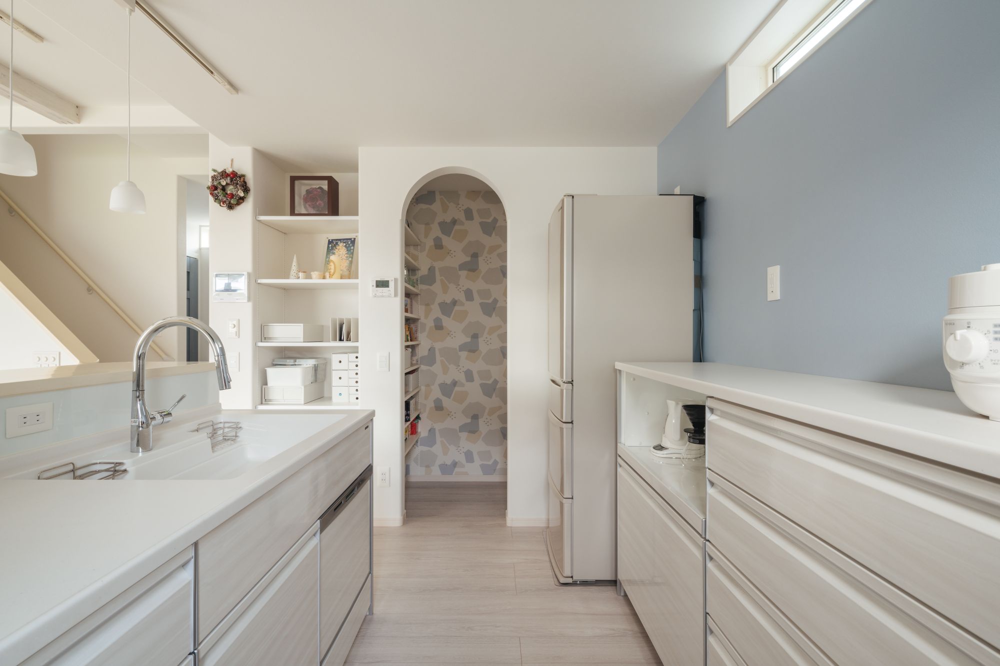 キッチン背面収納とアーチ開口のパントリーがつながる、家事動線を考えたキッチン空間