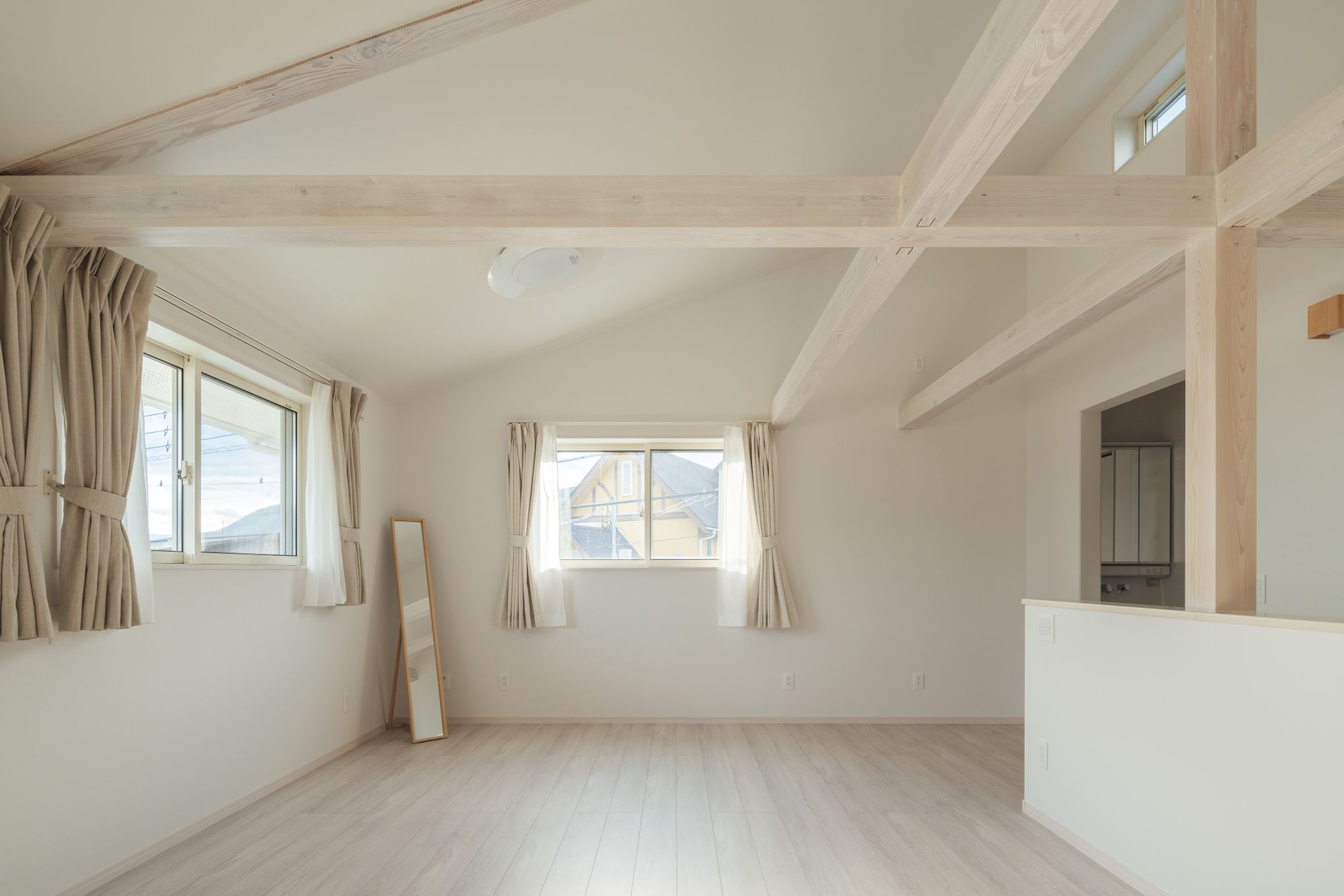 梁あらわしの勾配天井と二方向の窓から光が入る、明るく広がりのある個室