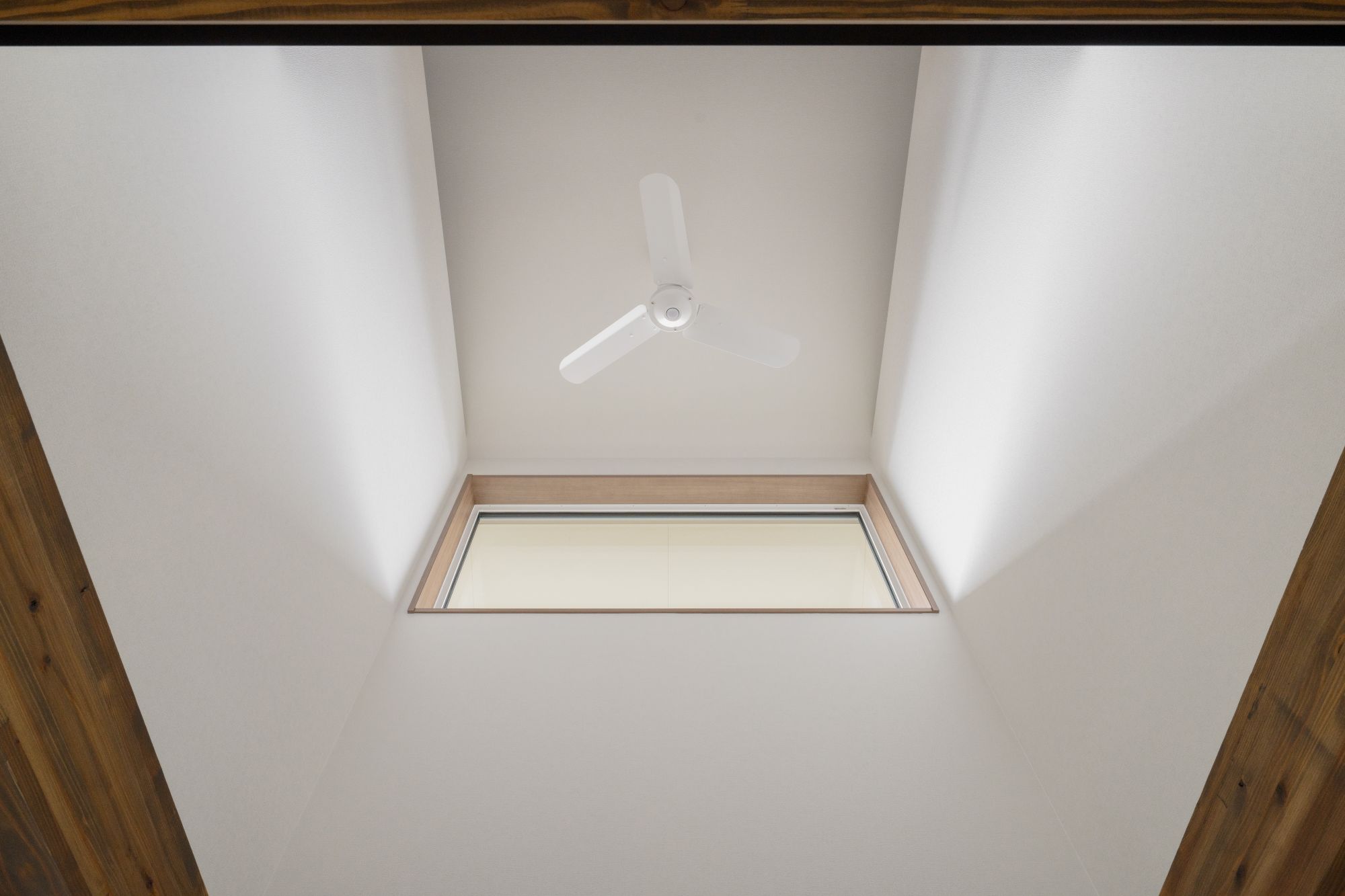 吹き抜けを下から見上げた高窓とシーリングファンの内観