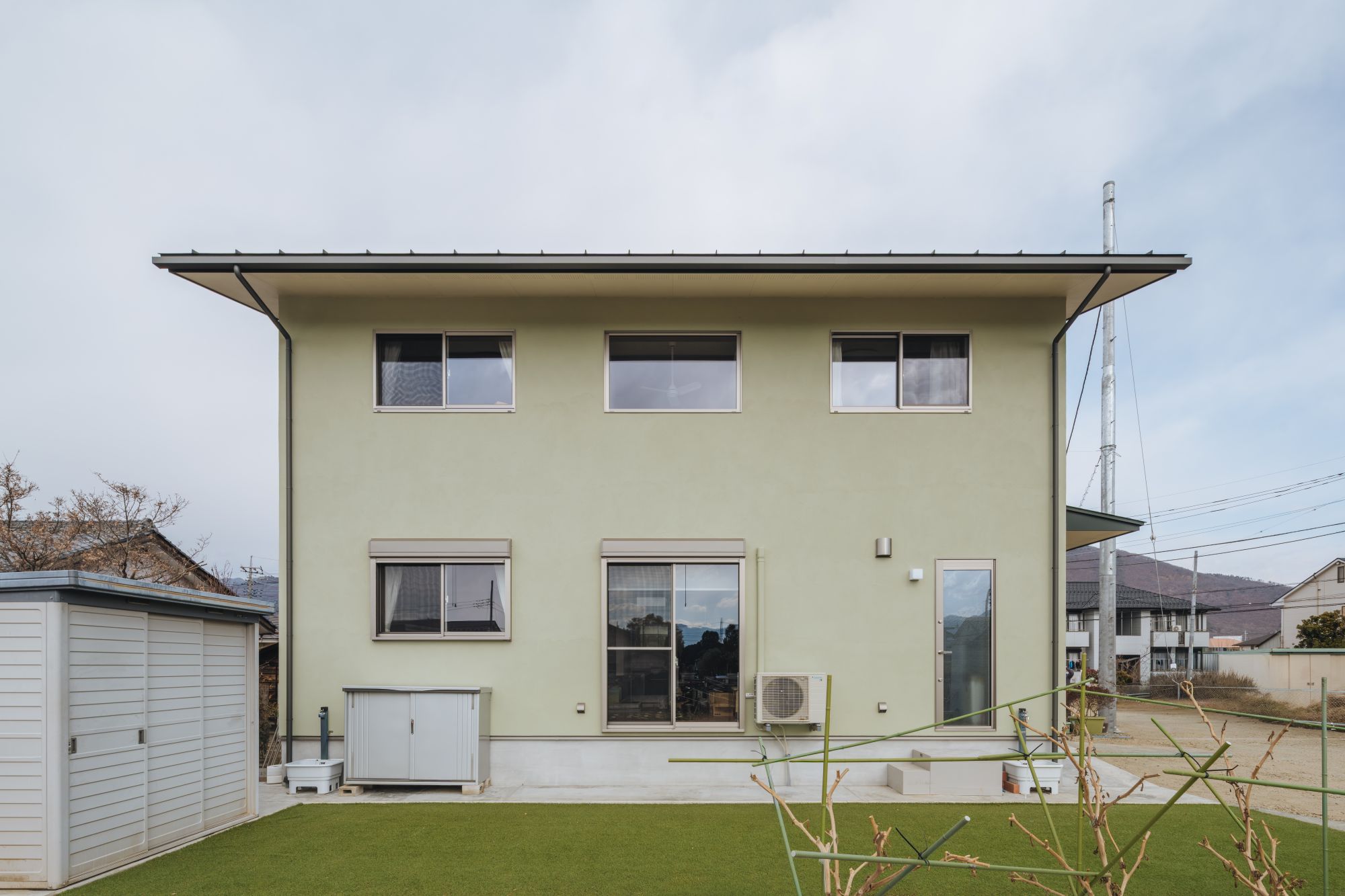 庭側から見た淡いグリーンの外壁の2階建て住宅外観