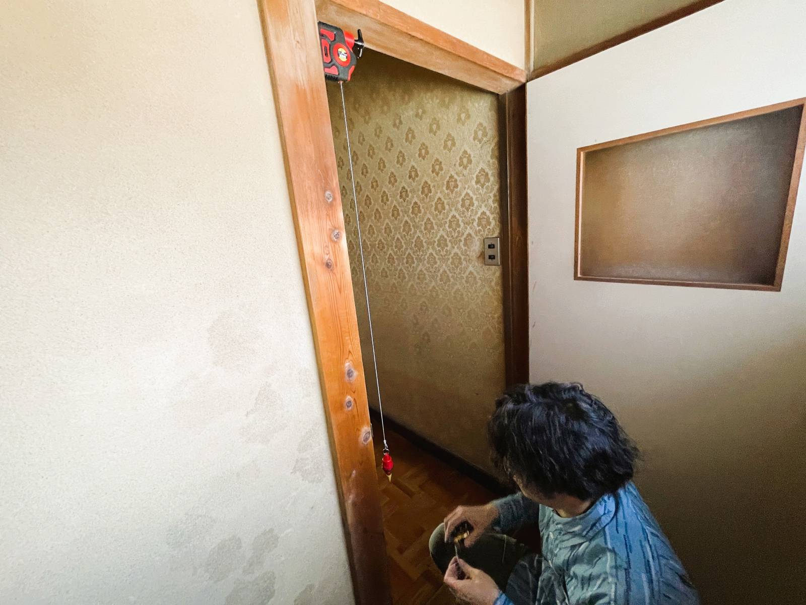 築45年の旧家屋で建物の歪みや不陸を下げ振りで確認している様子