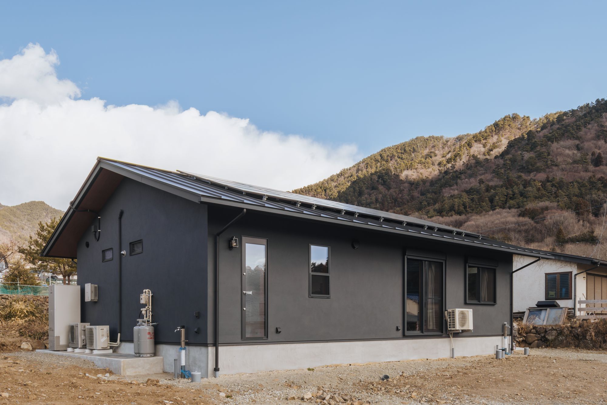 山並みを背景にした平屋住宅の外観斜め全景