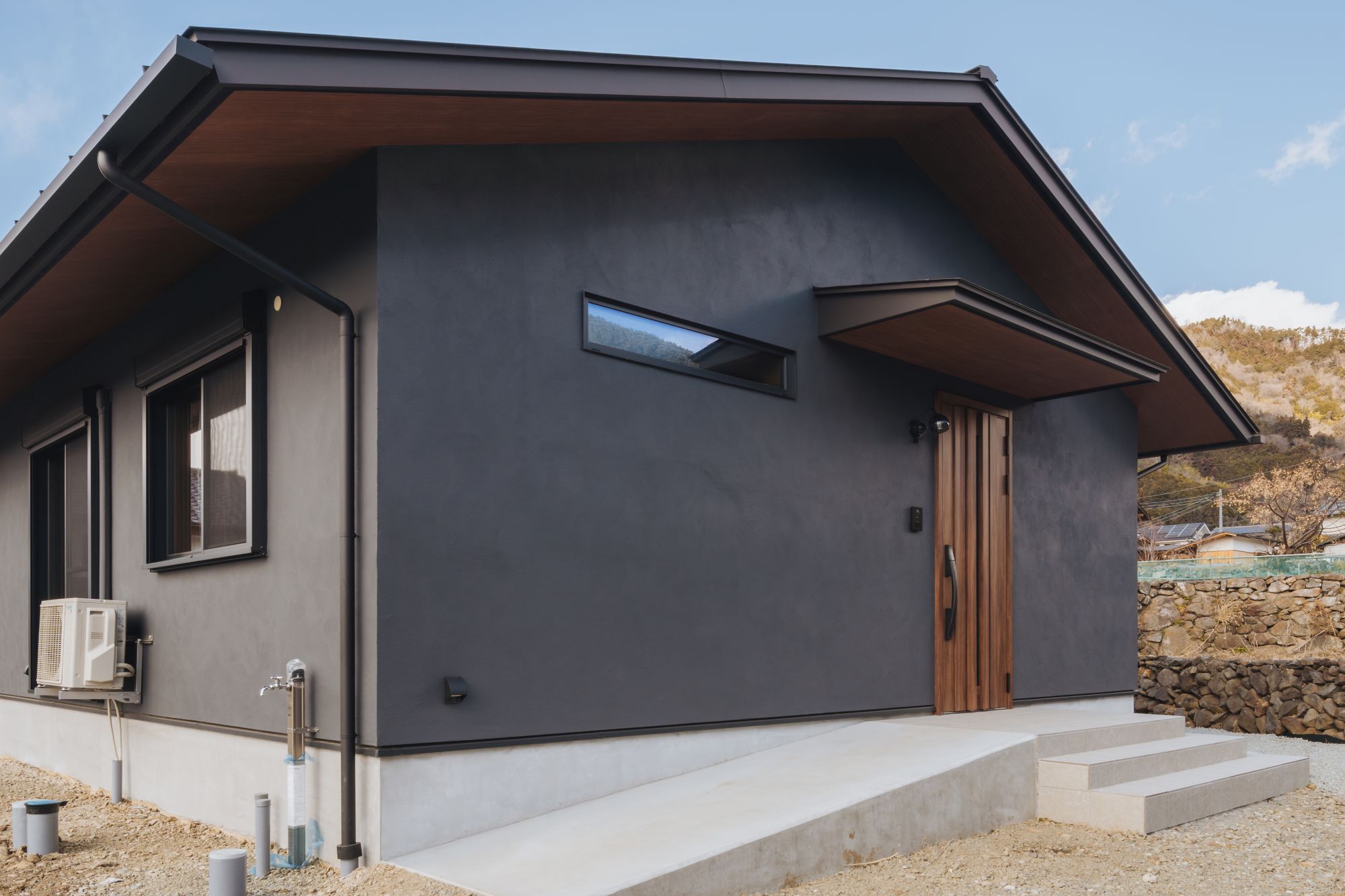 深い軒と木目玄関ドアのある玄関アプローチ