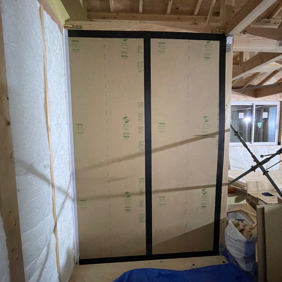 耐力壁の構造用面材継ぎ目に気密テープ処理を行っている施工状況