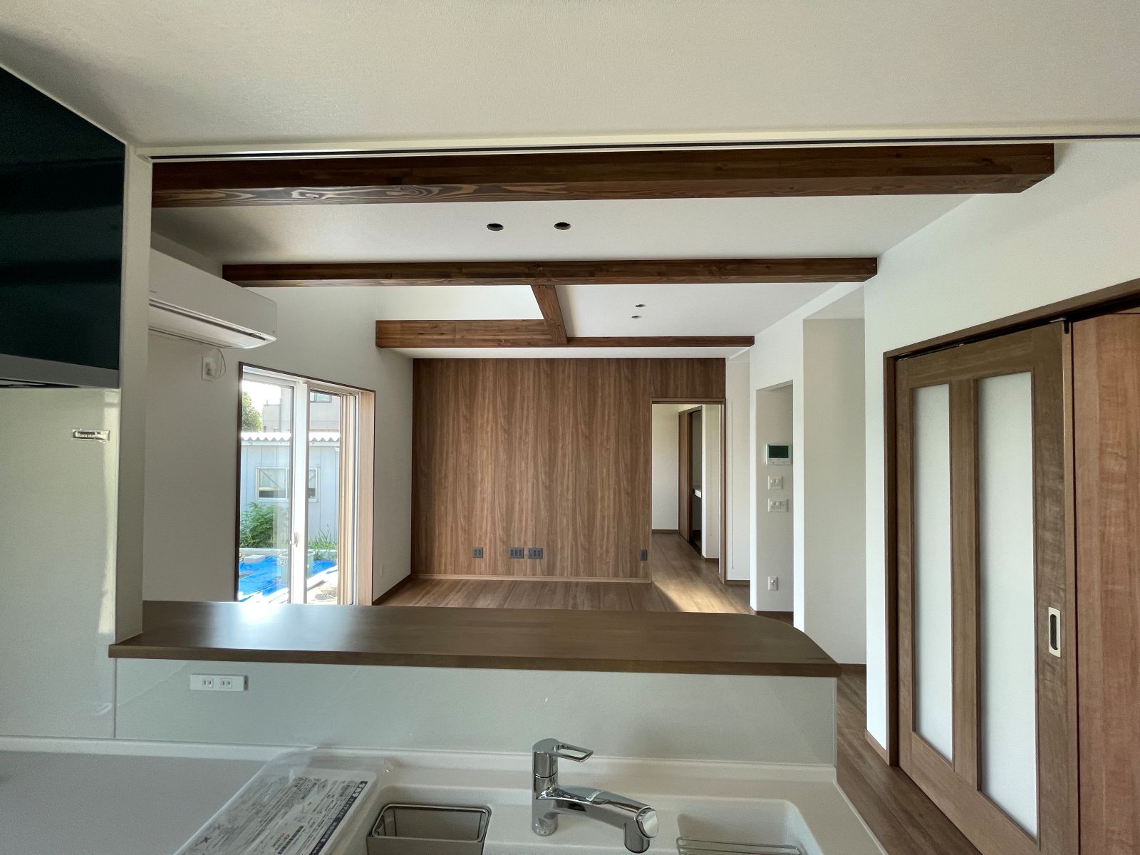 木目のアクセントクロスを採用したリビング空間（対面キッチンからの眺め）