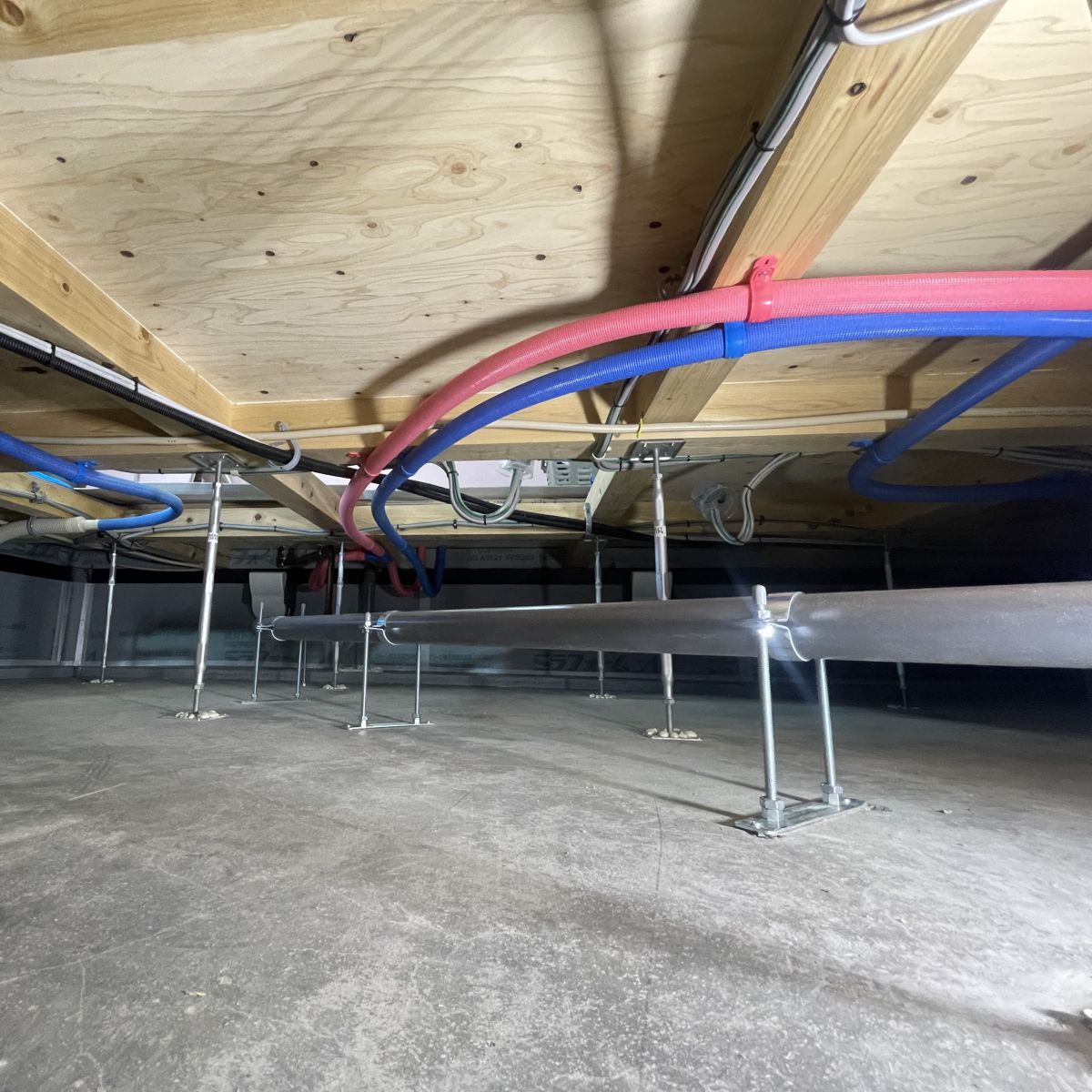 床下空間の配管と配線が整理され、人が点検しやすいよう確保された様子