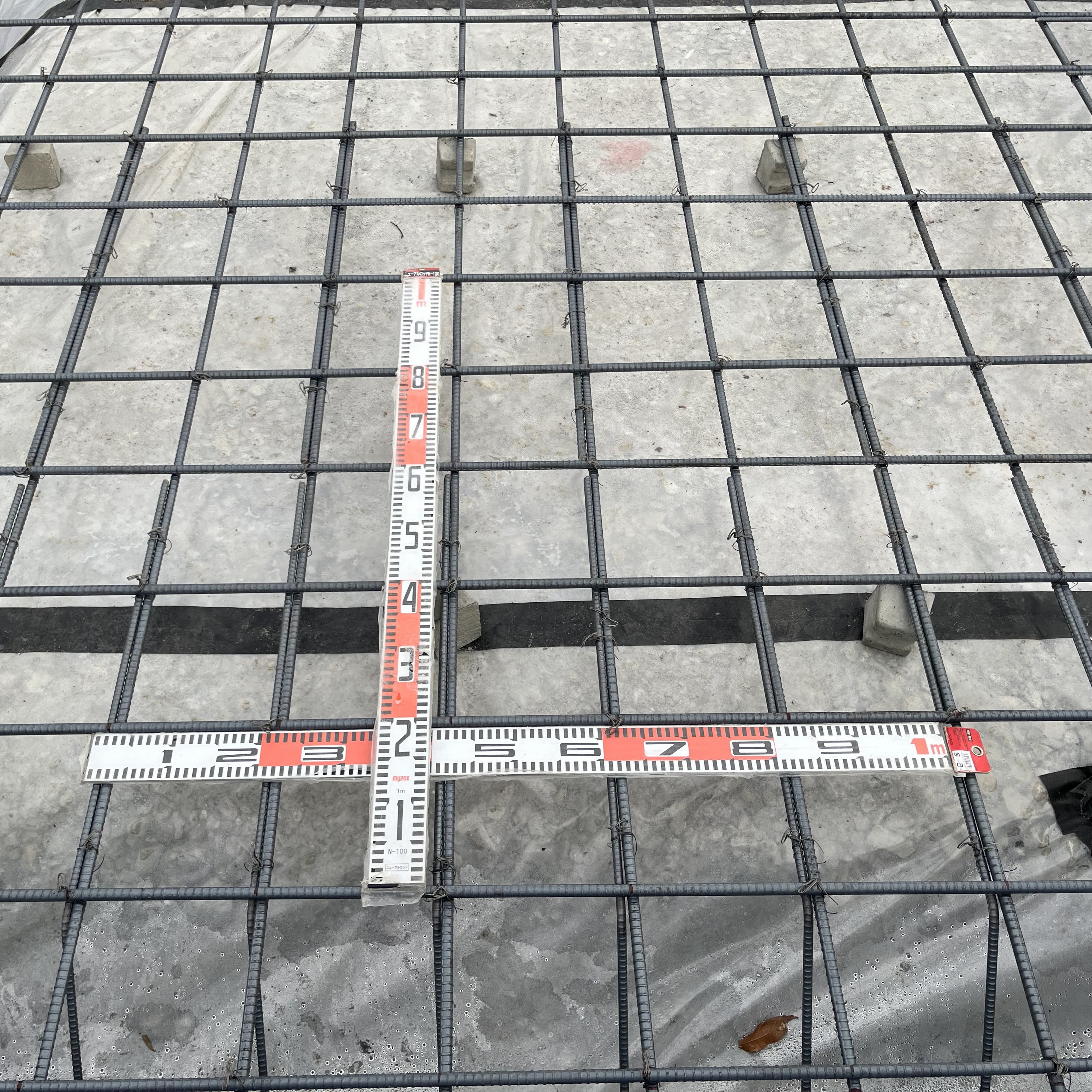 基礎配筋のピッチをスケールで確認している様子