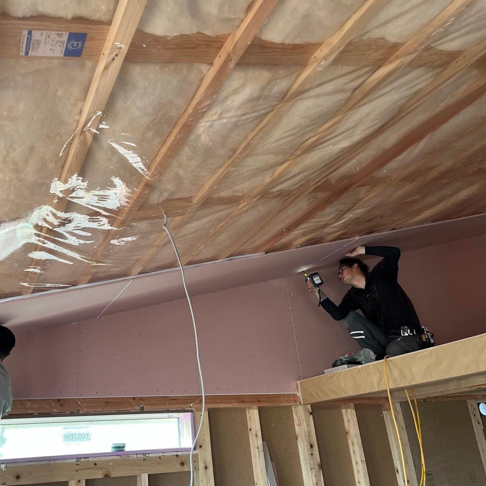 勾配天井の石膏ボードを施工している様子と大工の作業風景