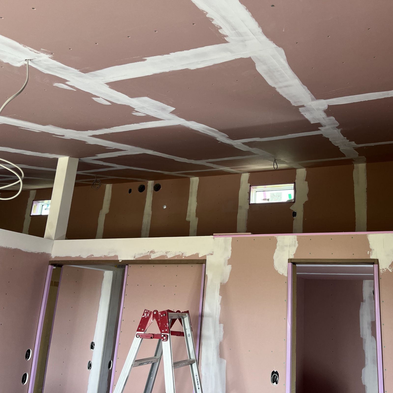 石膏ボードの継ぎ目やビス穴にパテ処理を行いクロス下地を整えている様子