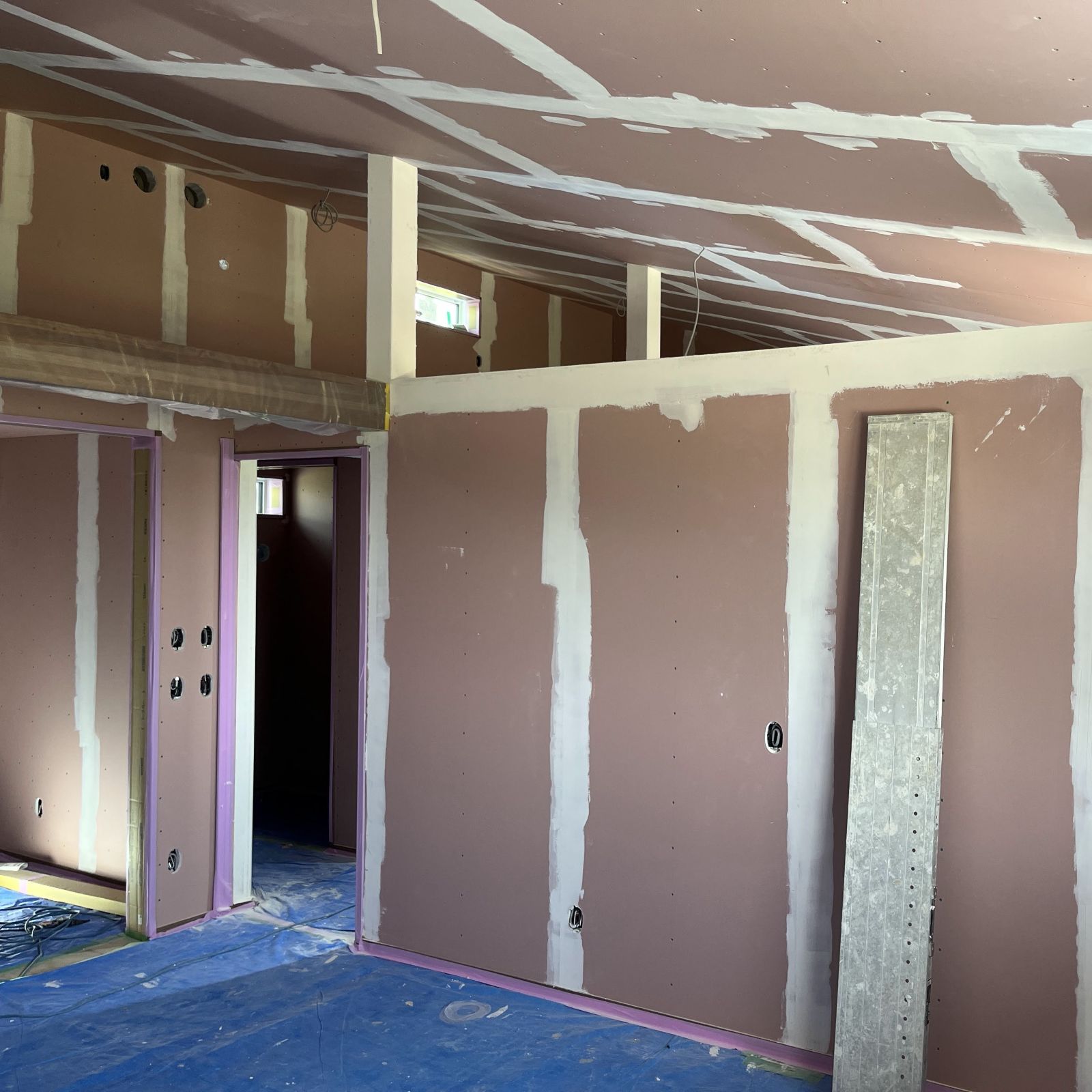 石膏ボードの継ぎ目やビス穴にパテ処理を行いクロス下地を整えている様子