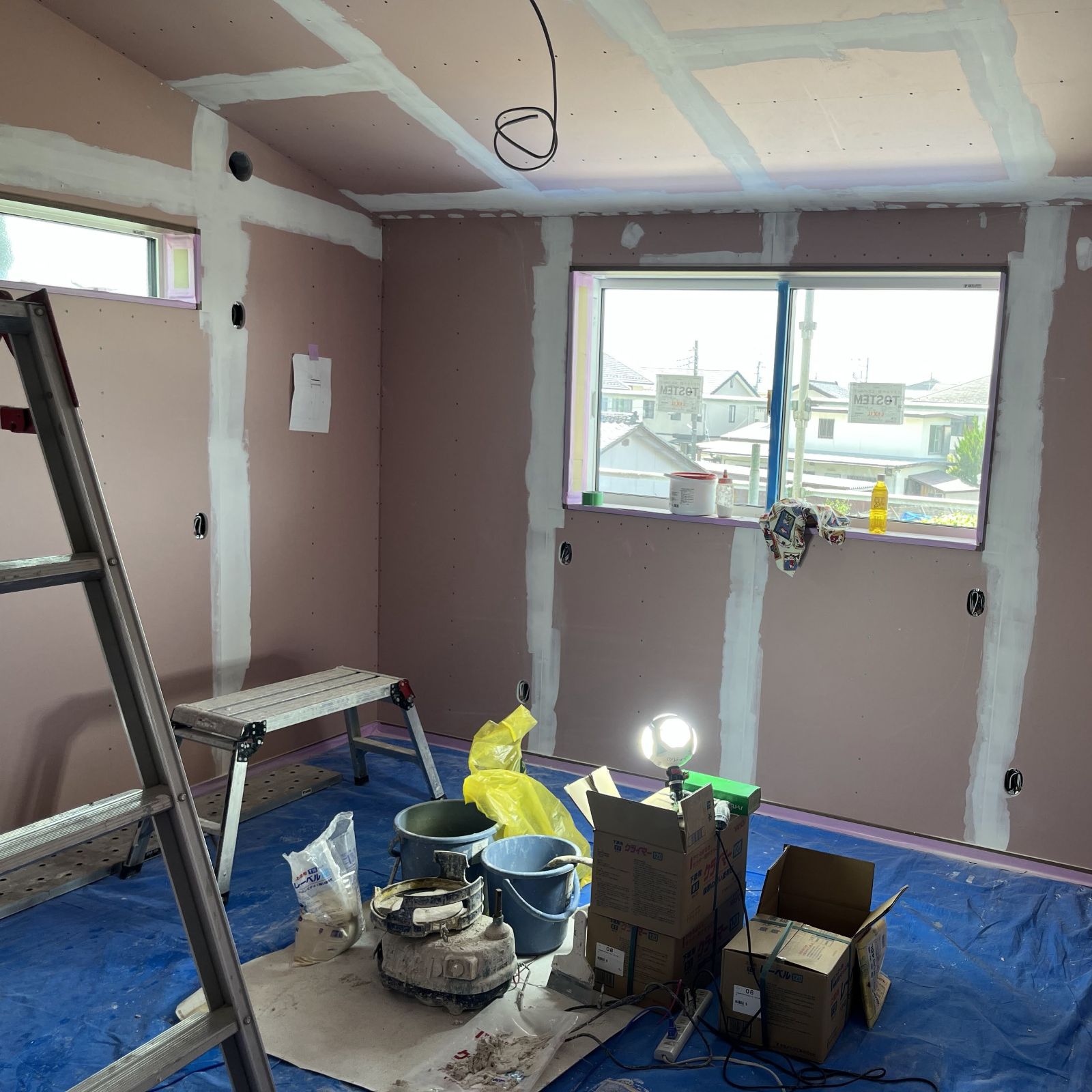 石膏ボードの継ぎ目やビス穴にパテ処理を行いクロス下地を整えている様子