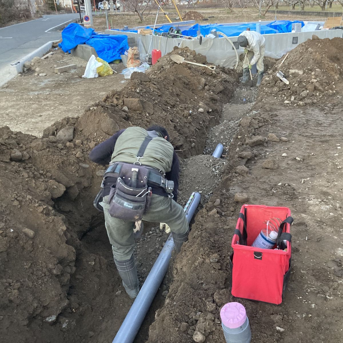 掘削した溝の中で排水管の勾配を確認しながら調整している様子