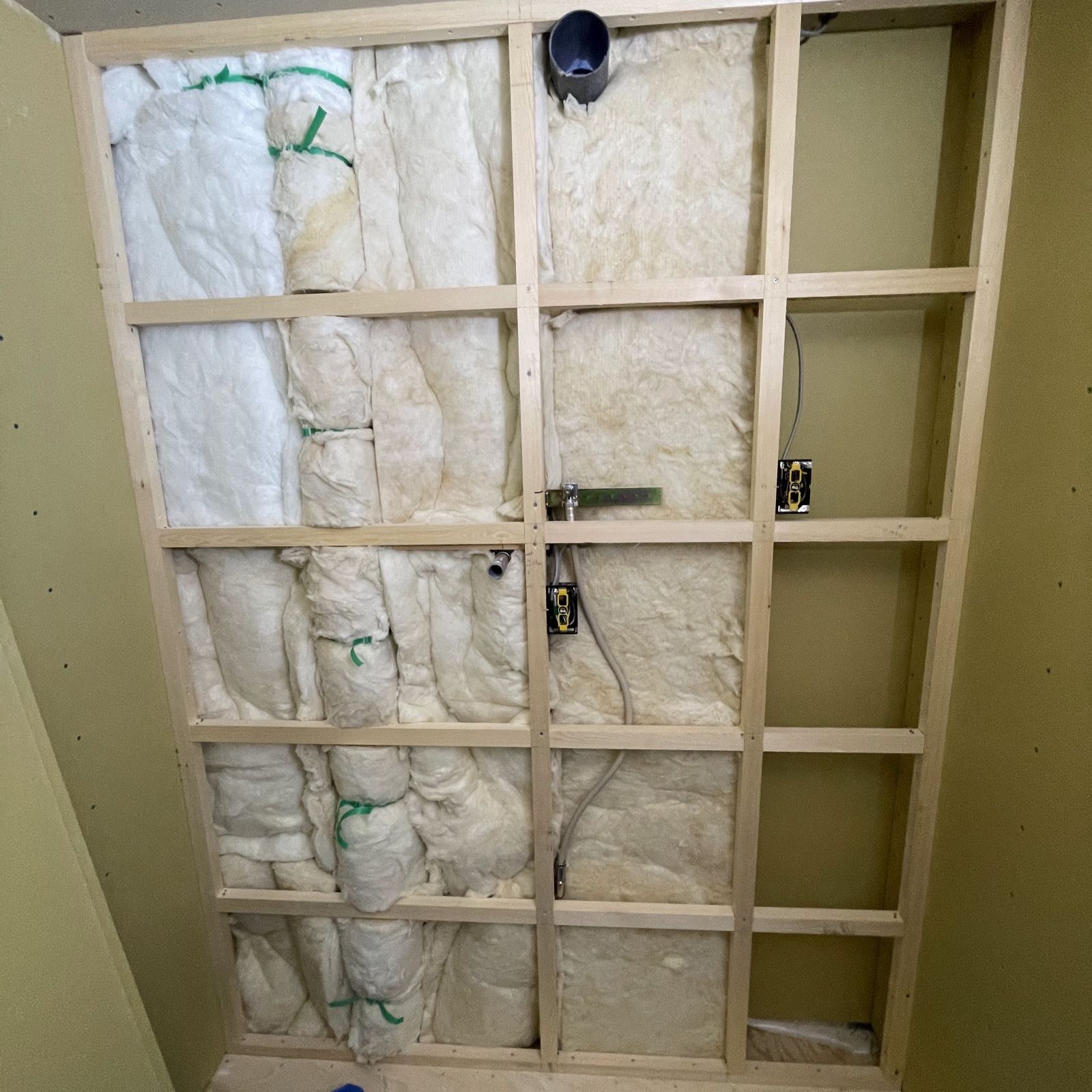 パイプシャフト内の配管をグラスウールで包み、排水音を軽減している様子