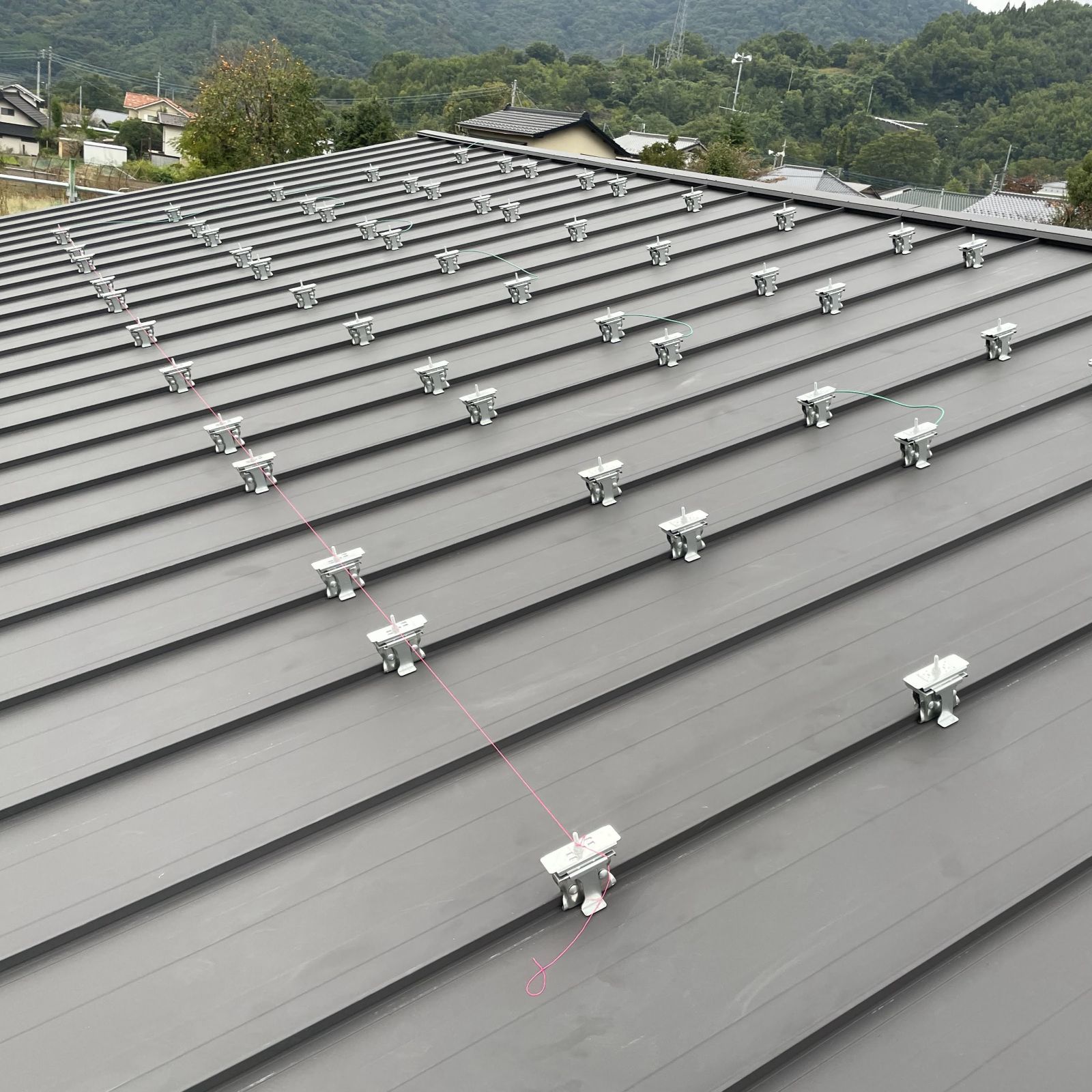 糸を張って基準線を出し、太陽光パネルの固定金具を正確に配置している様子