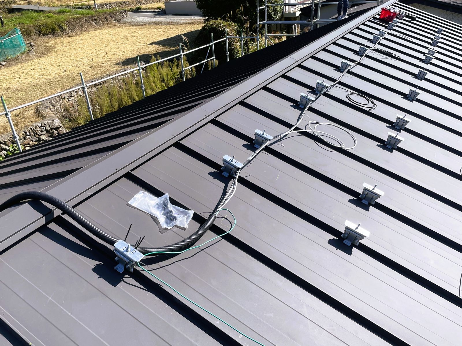 立平葺き屋根で太陽光発電設備の配線ルートと配管処理を行っている様子