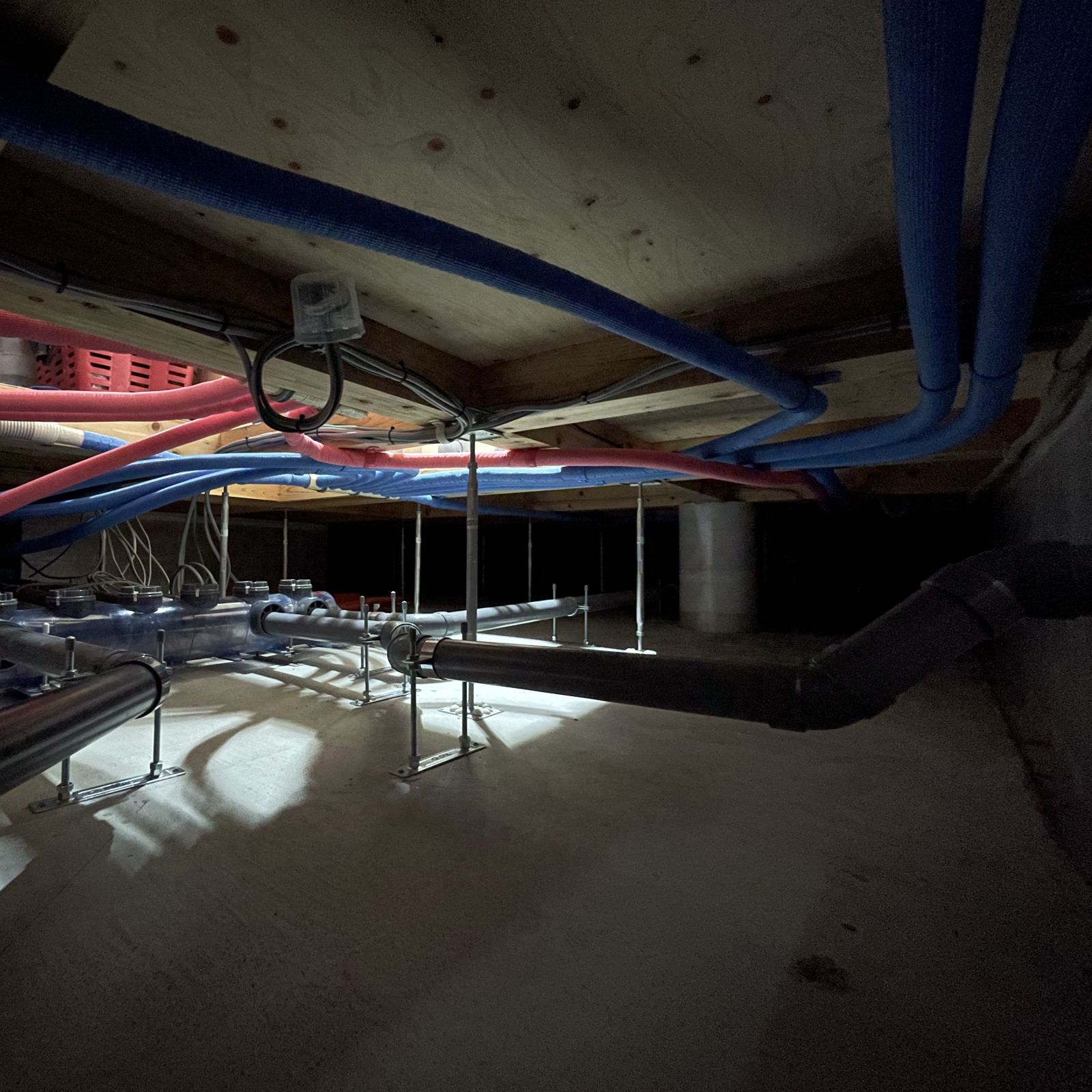 床下空間において支持金物で浮かせて整然と施工された給排水配管の様子