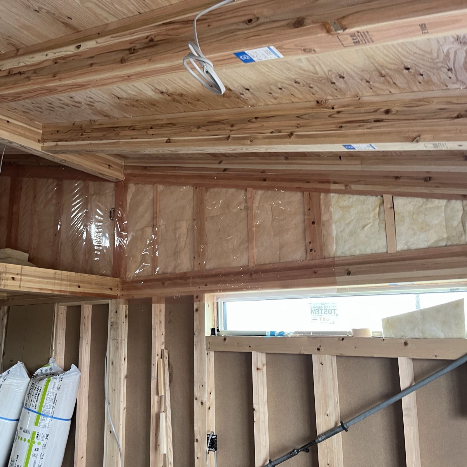 小屋裏の壁部分に断熱材を隙間なく充填し気密シートを施工している様子