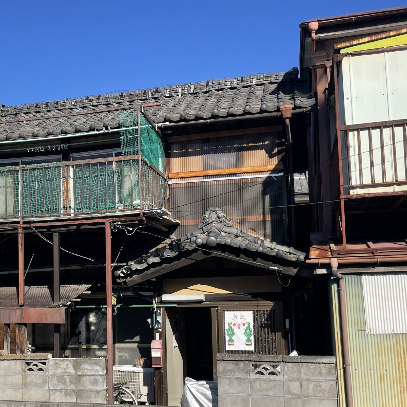 劣化した土壁を木材とポリカーボネートで仮補修している外観