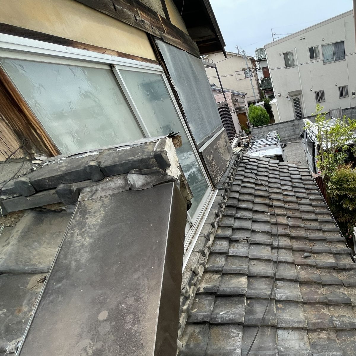 劣化した外壁部分を鉄板や合板で仮補修している外観