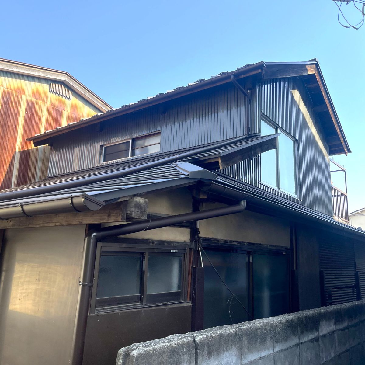 屋根葺き替えと外壁鉄板施工が完了した住宅外観