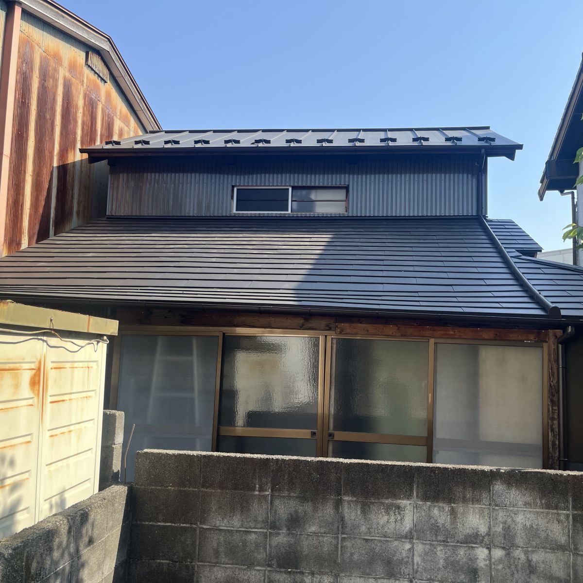 屋根の葺き替えと外壁鉄板施工が完了した住宅外観