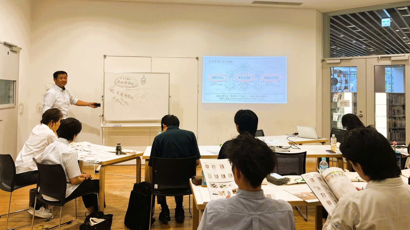 オスモ&エーデル株式会社の講師が木部塗装の3つの役割を説明している勉強会の様子