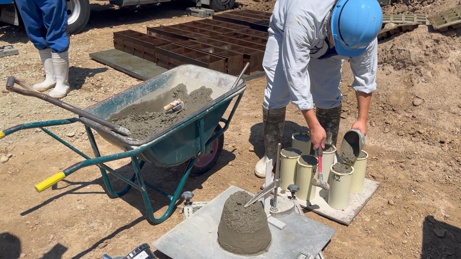 現場に届いた生コンクリートを型へ詰め、圧縮強度試験用の供試体を作製している様子