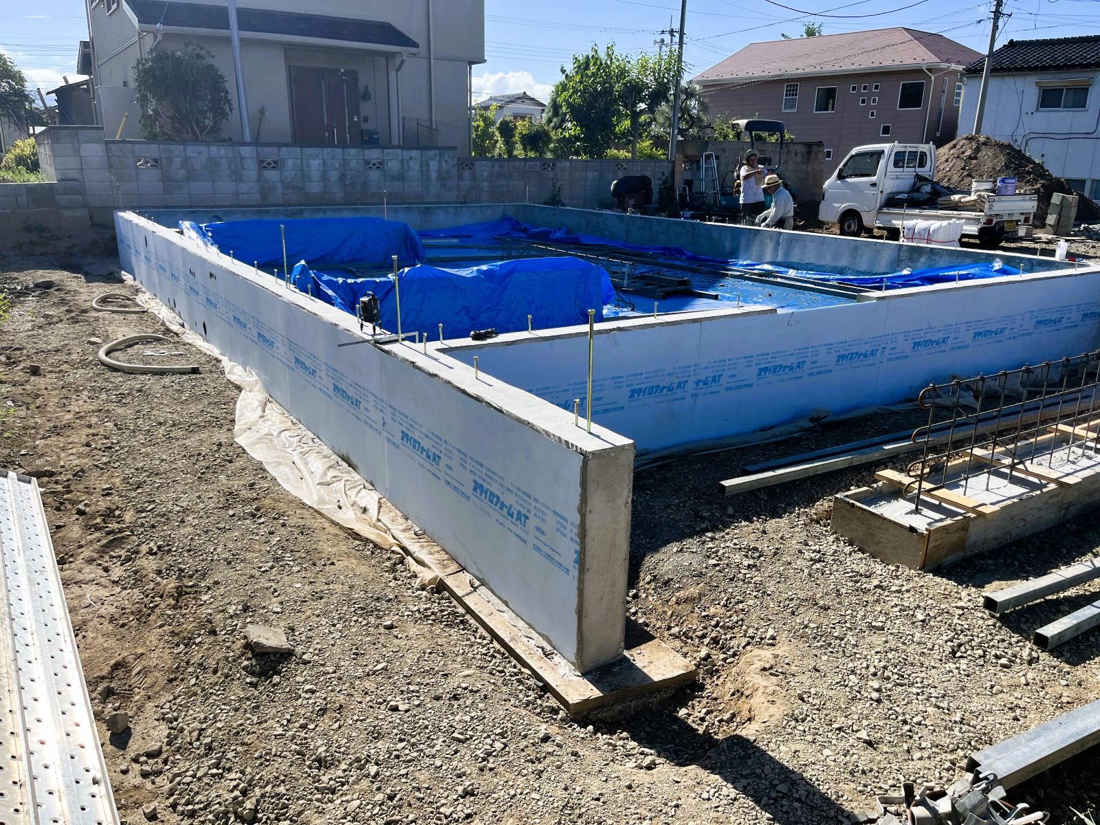 コンクリート打設後の新築住宅の基礎全景と、外周に施工された基礎外張り断熱材