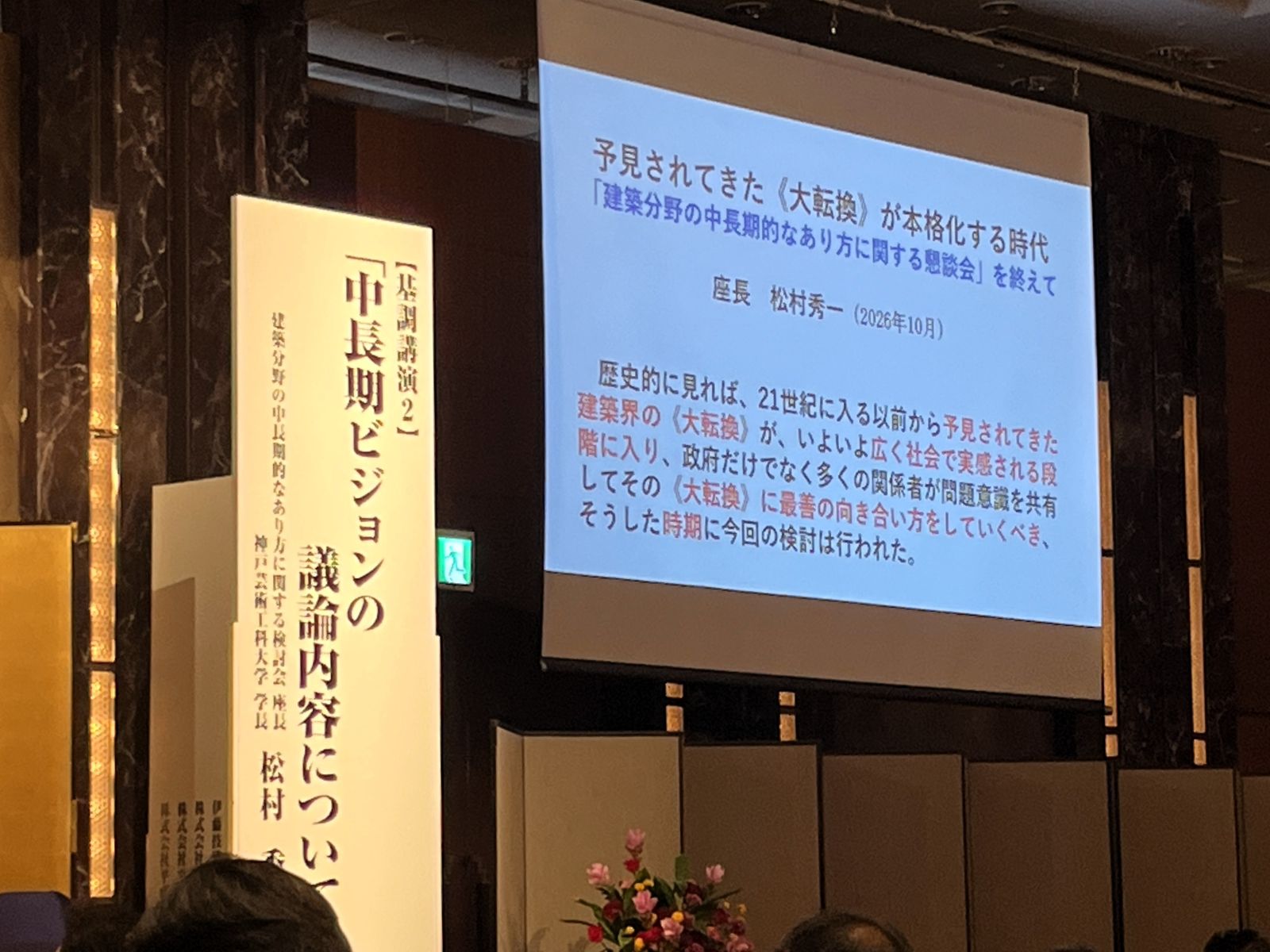 松村秀一さんの講演会場に掲げられた中長期ビジョンの演題と投影スライド