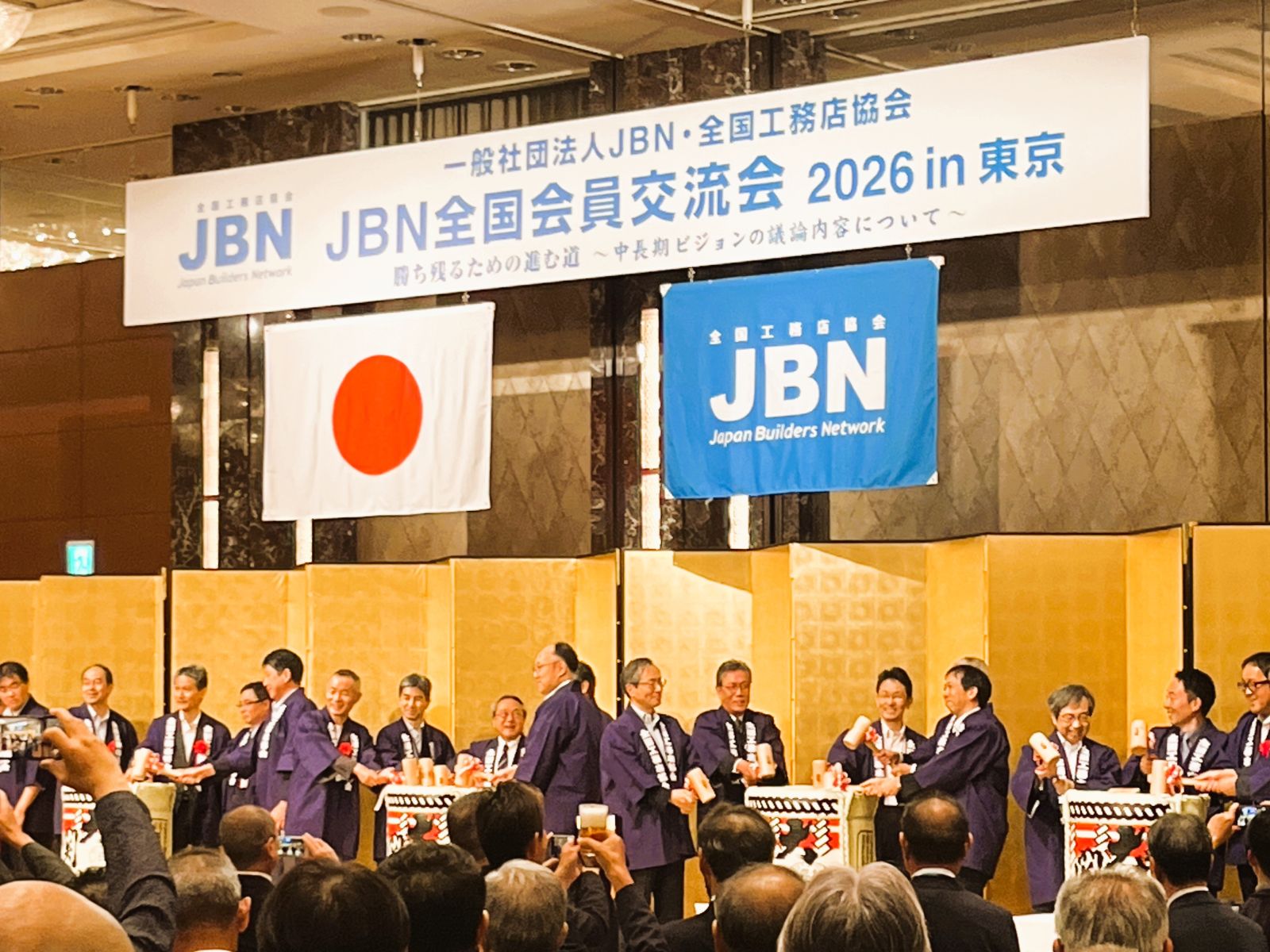 JBN全国会員交流会の懇親会で登壇者が酒樽を囲んで鏡開きをする様子